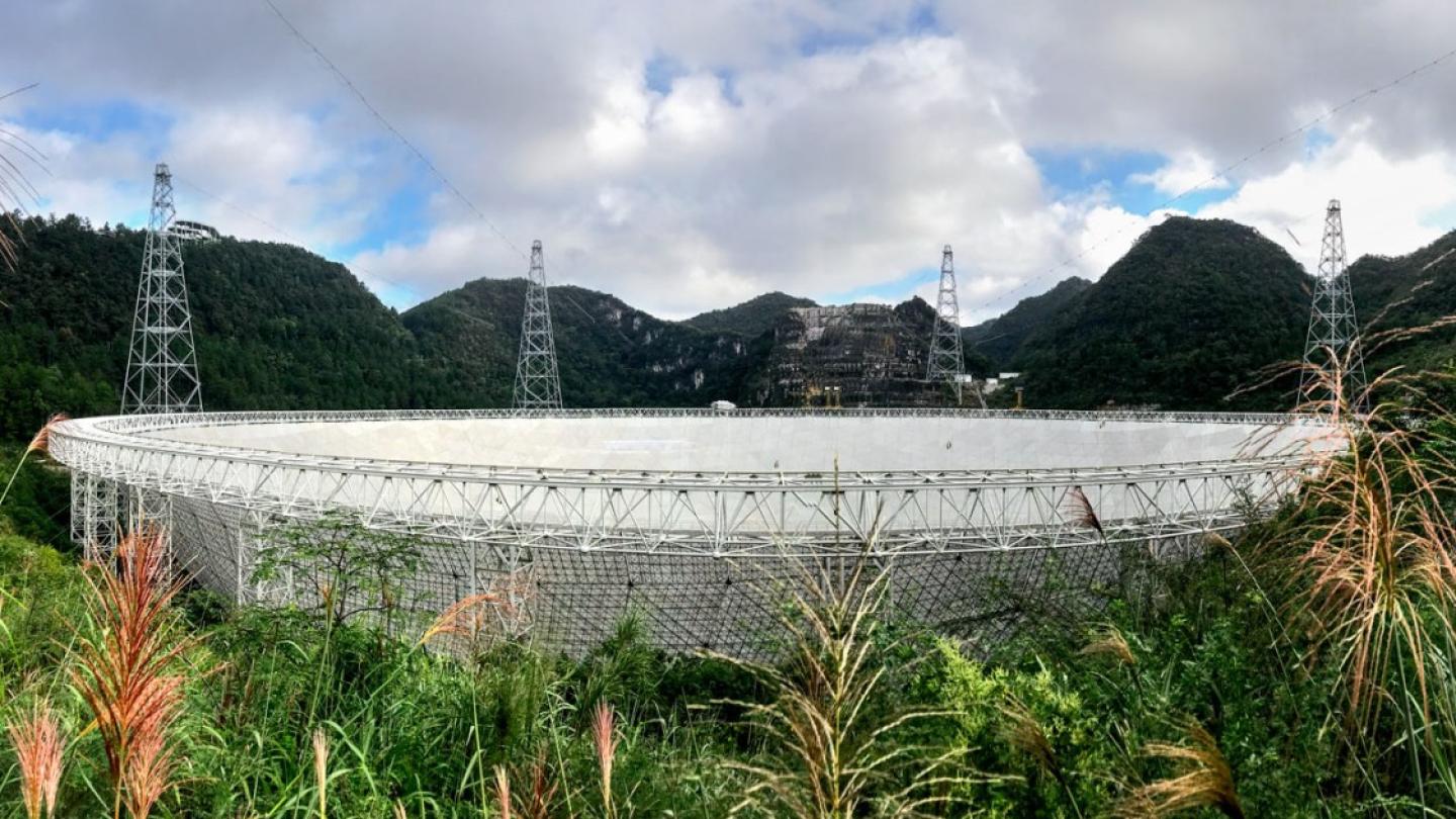 Giant white dish-shaped structure set in lush hills