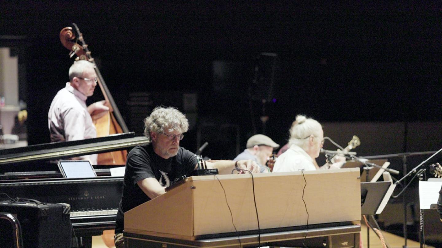 Four people on a stage, with instruments