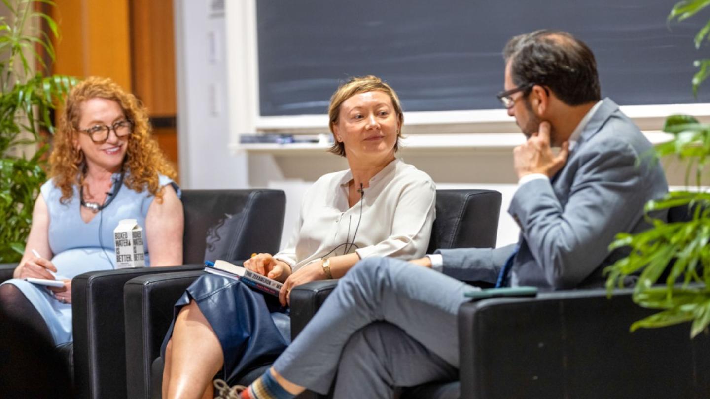 Three people sit in armchairs, part of a panel discussion event